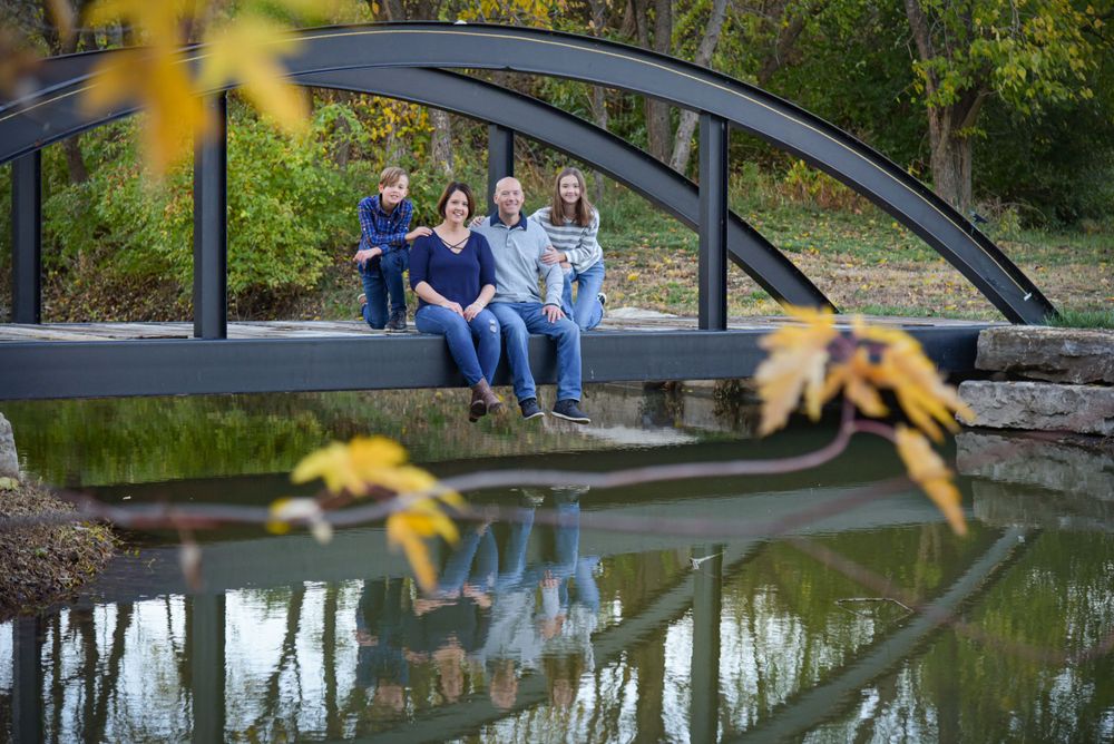 A peaceful scene of people sitting on a curved bridge over a pond with yellow flowers.