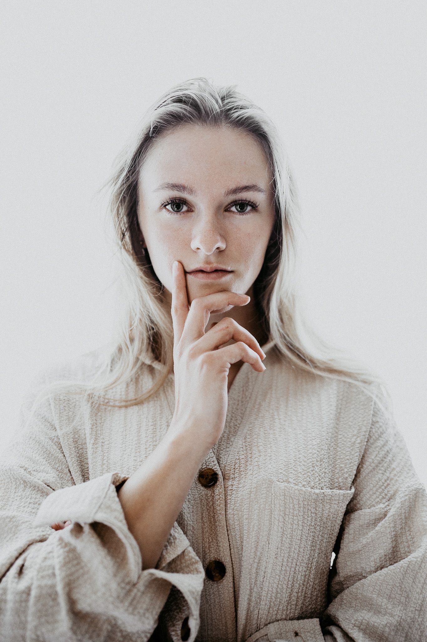 Frau mit blonden Haaren vor einem weißen Hintergrund im Portrait.