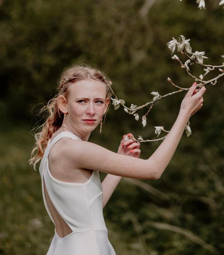 Æterisk udendørs portrætserie med en flydende hvid kjole og forårsblomster.
