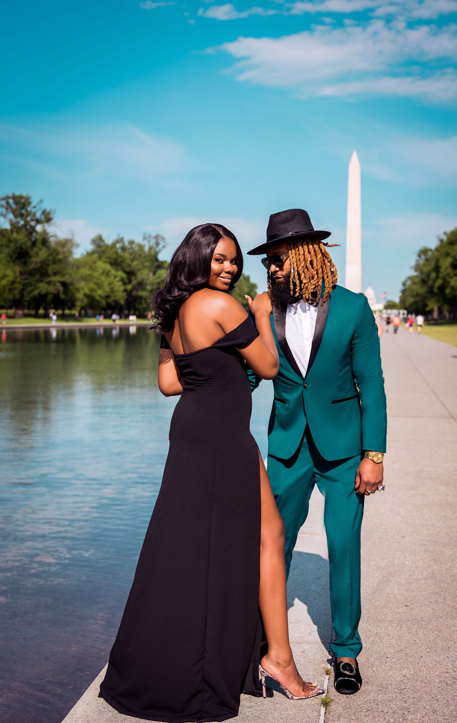 Couple in formal attire poses by reflecting pool with Washington Monument in background.