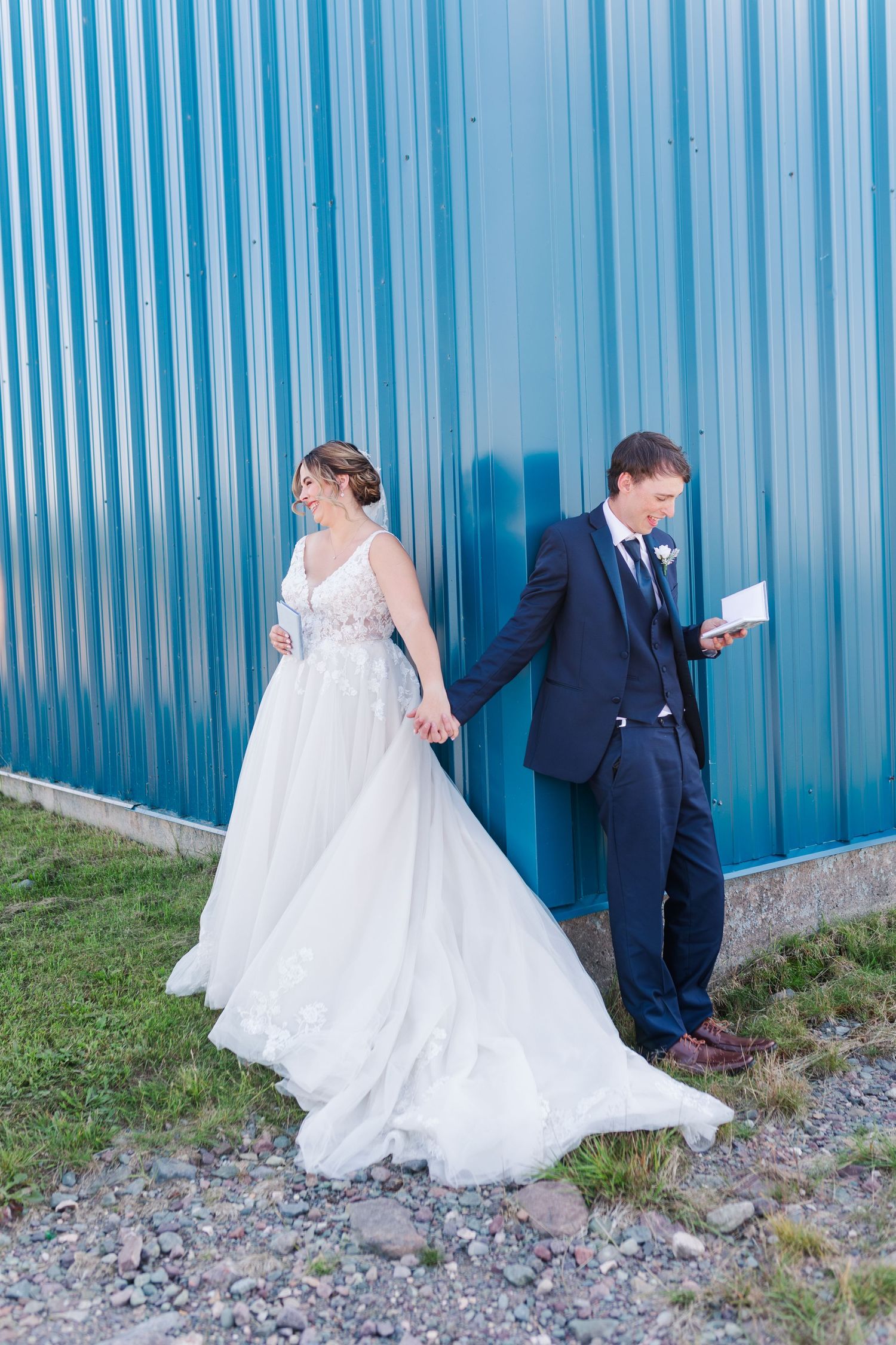 Couple poses against blue corrugated metal wall for first look wedding photos.