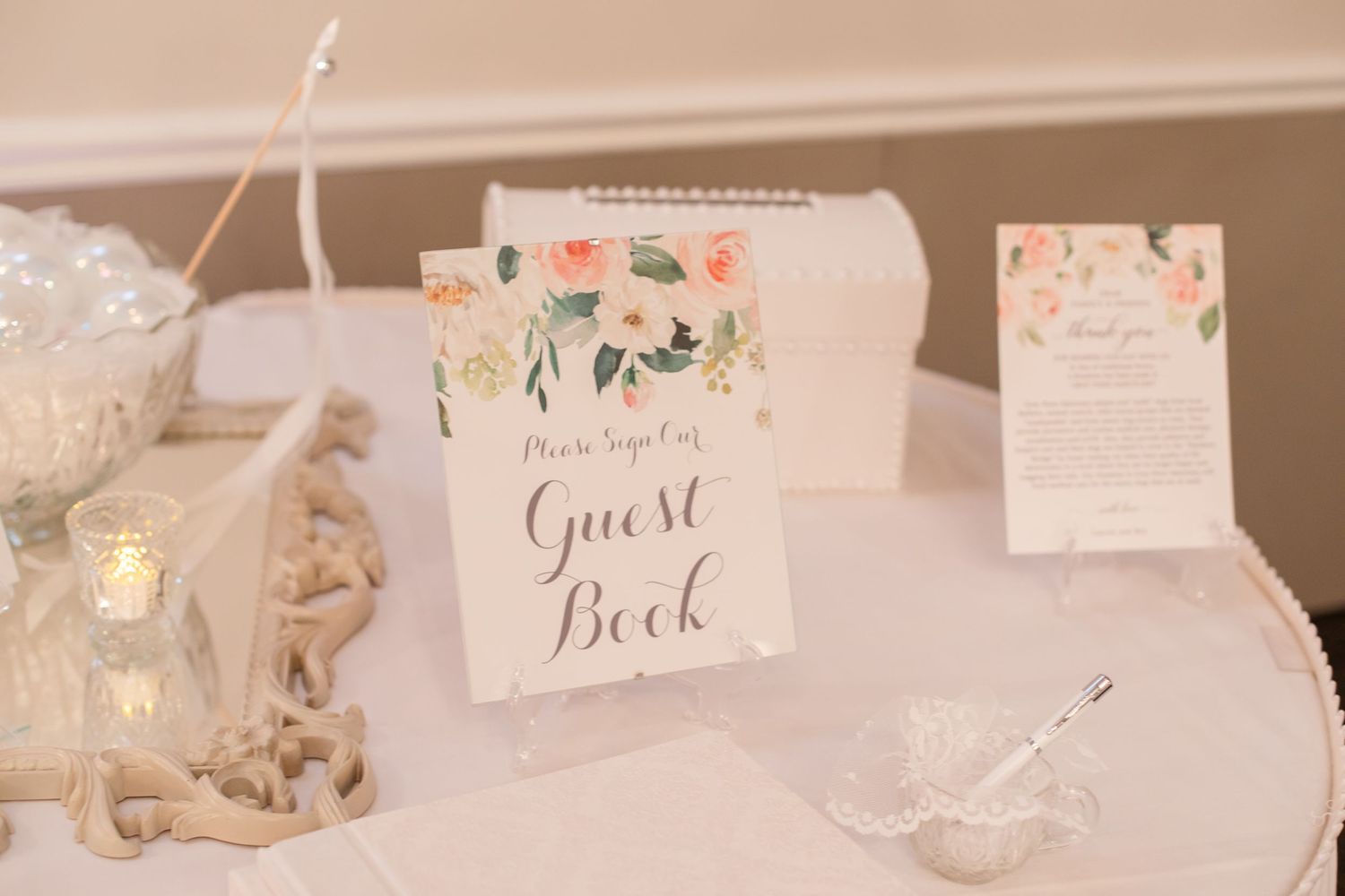 Wedding guest book table decorated with elegant calligraphy signs and soft romantic decor.