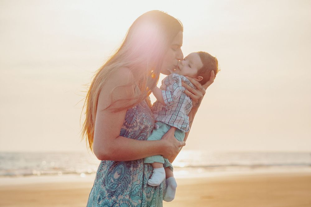 Family plays together on beach at sunset.