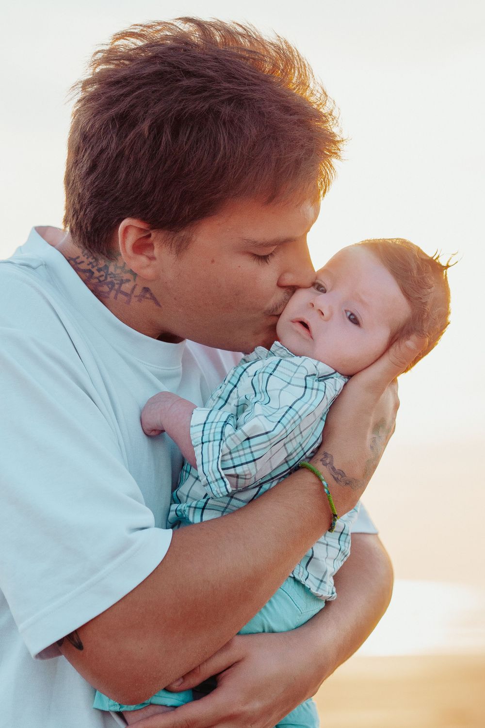 Parent and child share tender moment at sunset outdoors.