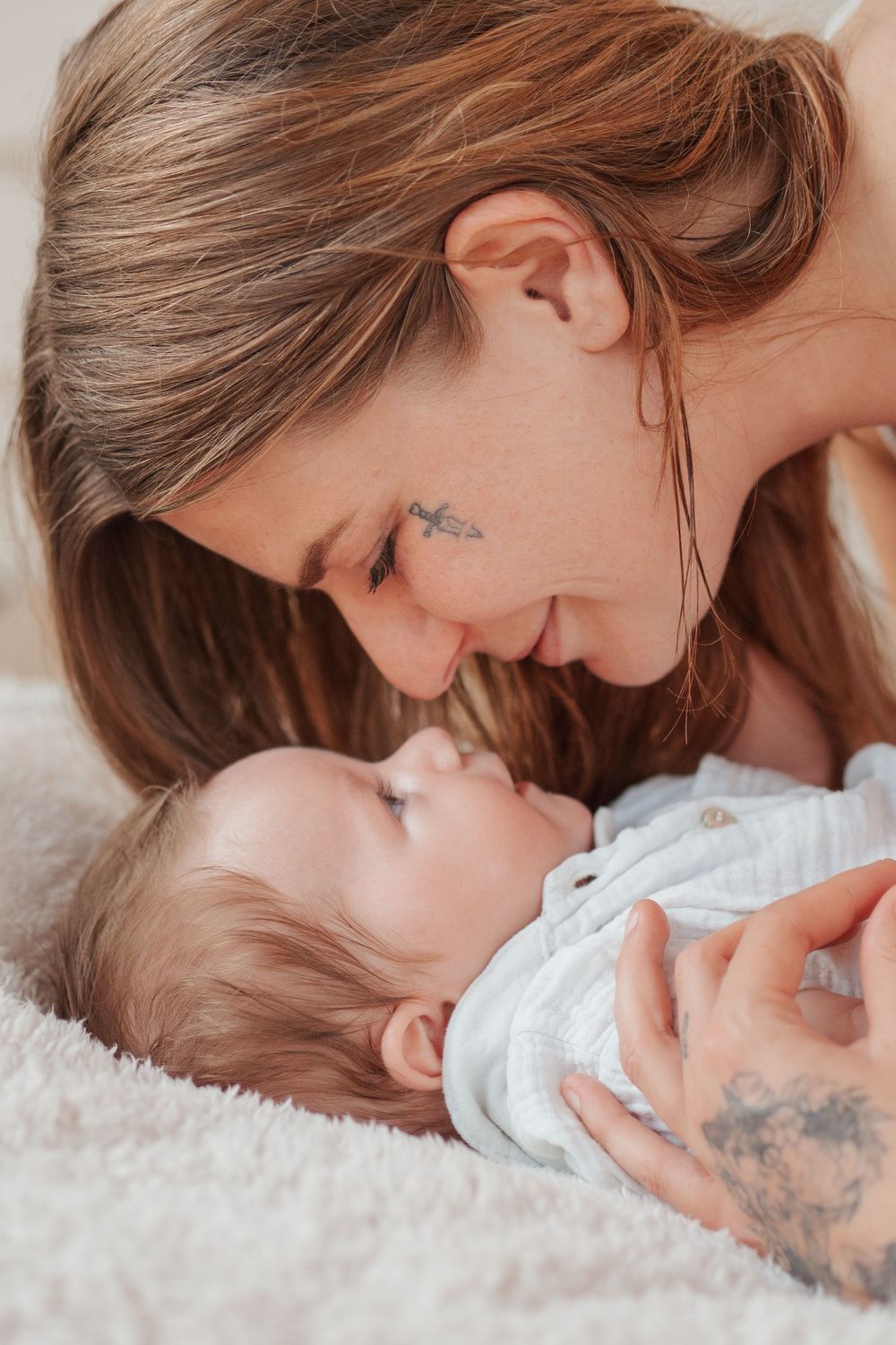 Intimate family moment captured on soft white blanket.