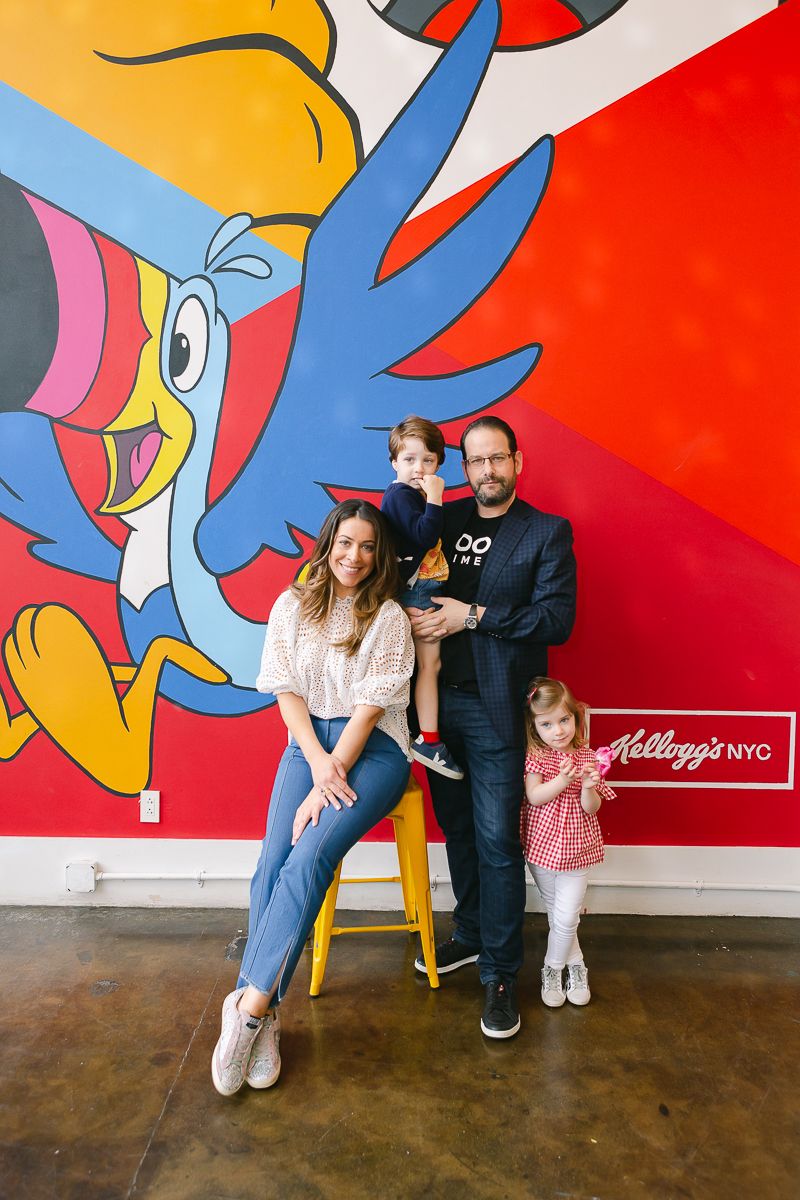 a candid view of a family of four standing in front of a colorful mural at Kellogg's NY Manhattan during a birthday