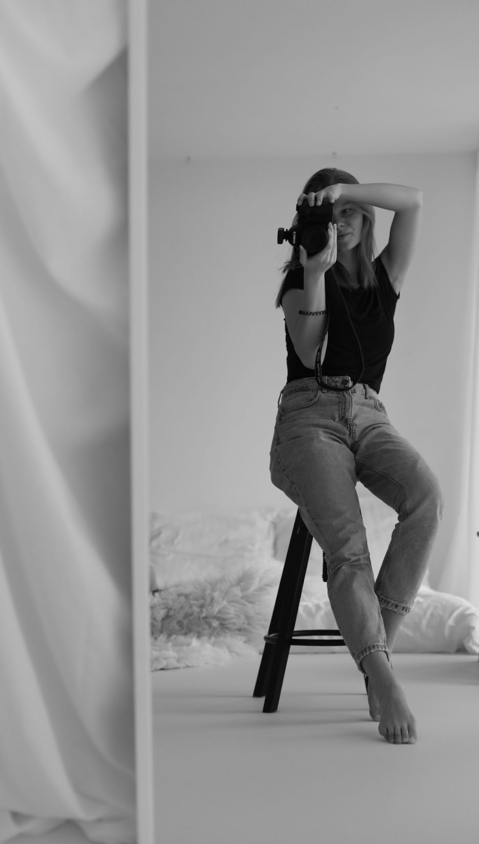 Black and white portrait of photographer sitting on stool taking pictures.