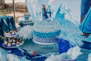 Blue and white Frozen themed party decorations with snowflake accents and dessert display.