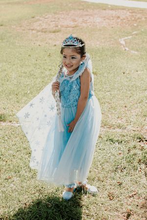 A sparkly blue princess dress twirls on a sunny grass lawn.