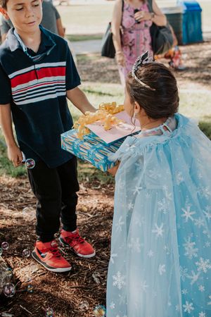 Children playing outdoors with someone wearing a blue snowflake dress.