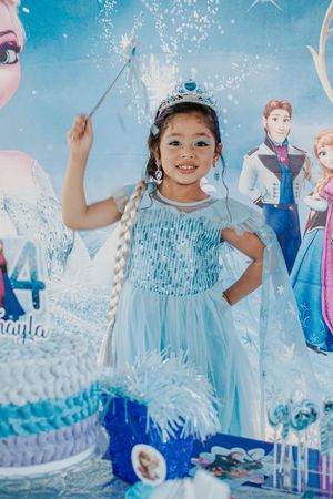 Birthday party scene with Frozen themed decorations and magical blue lighting.