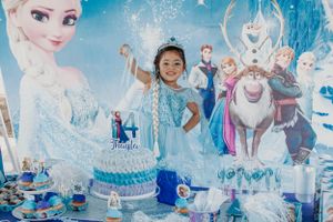 Frozen-themed party backdrop with sparkly blue decorations and character cutouts creating a magical winter atmosphere.