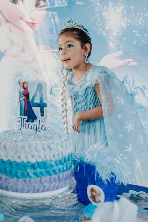 Blue and white tiered birthday cake decorated with snowflakes and winter-themed details.