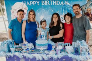 Outdoor birthday party with blue and white decorations under a Happy Birthday banner.