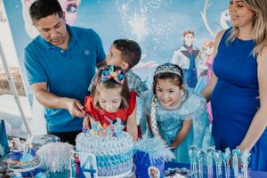 Family members gather around a decorated birthday cake at Frozen themed celebration.