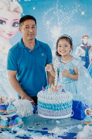 A Frozen-themed birthday celebration with a decorated cake and movie character backdrop.