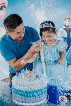 A touching moment at a Frozen-themed birthday party with a beautifully decorated blue cake.