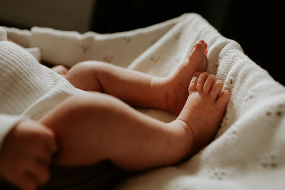 Tiny bare feet of an infant resting on soft white fabric.