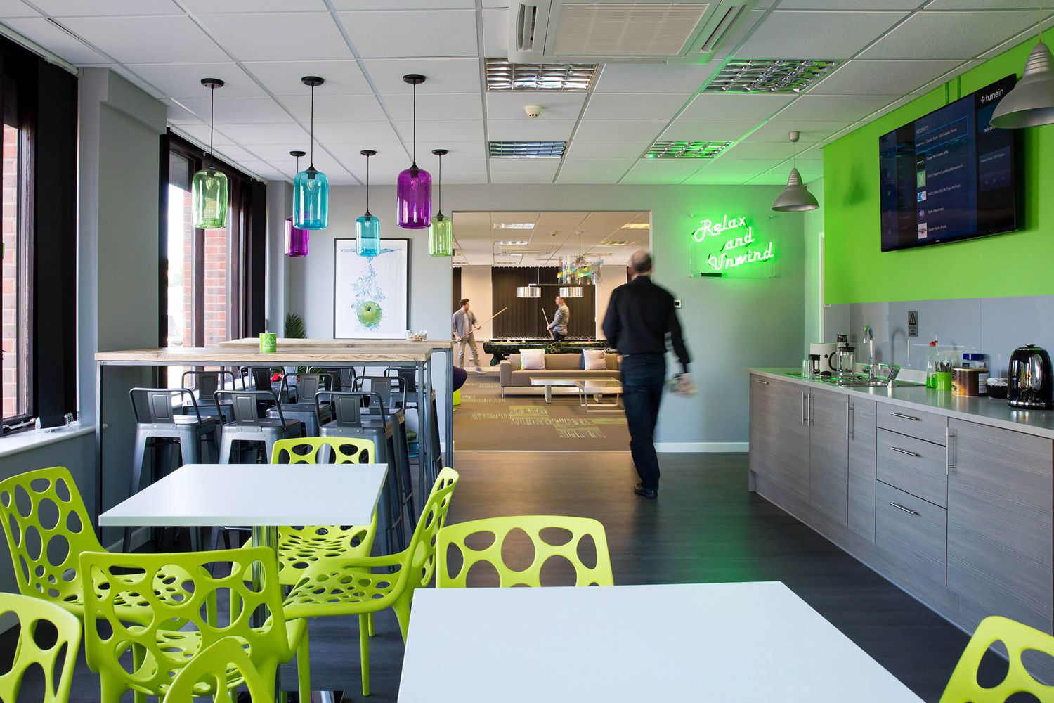 Modern office break room with green chairs and colorful pendant lights during business branding photoshoot.
