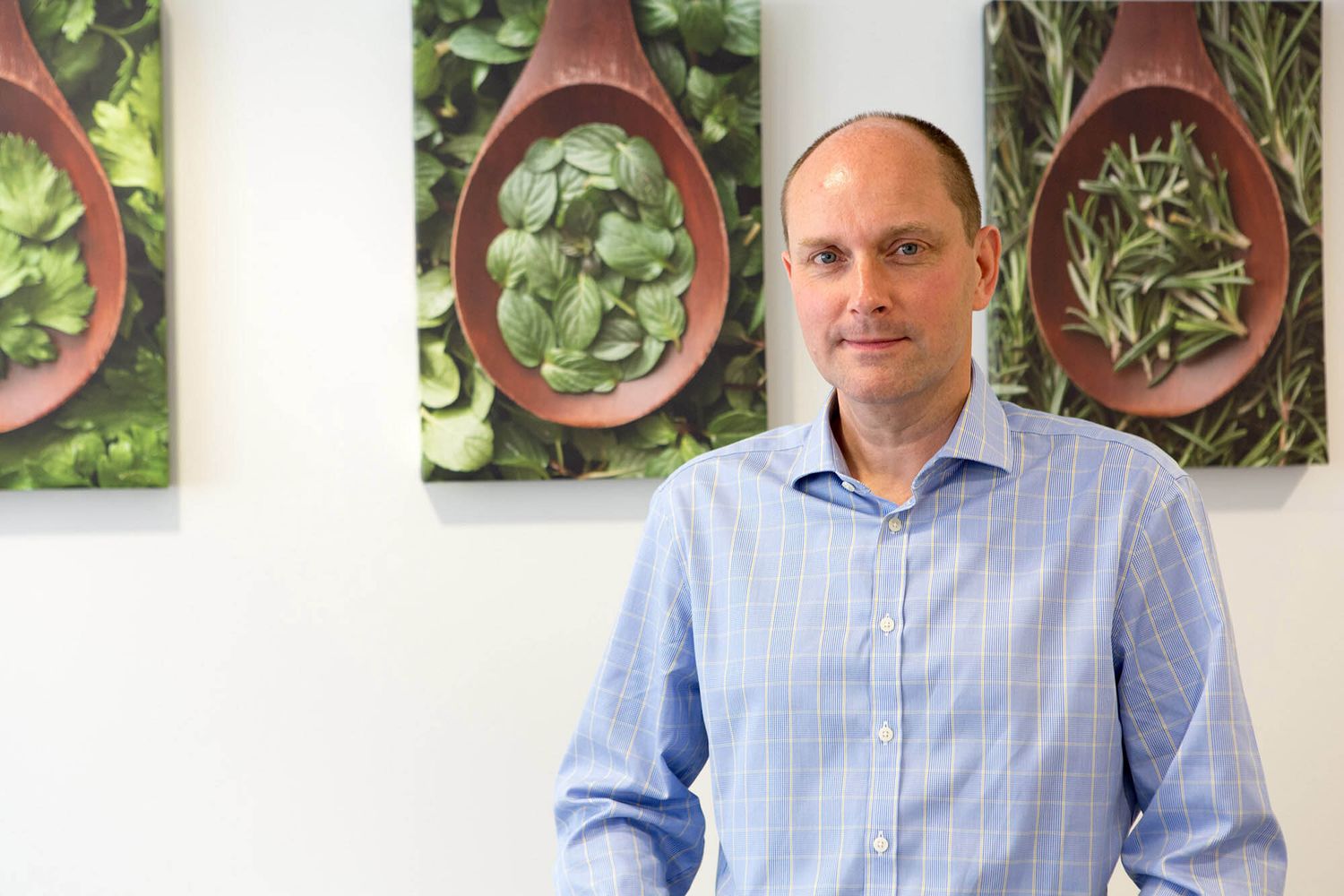 Professional standing in front of decorative wooden spoon wall art during business branding photoshoot.