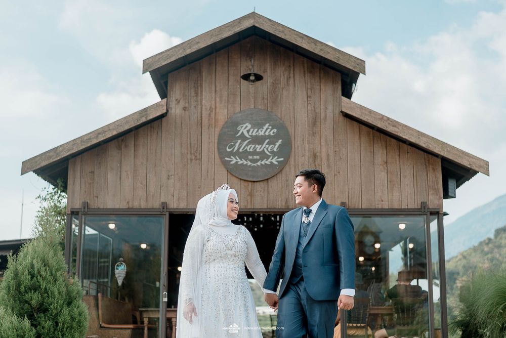 A couple stands together outside a rustic wooden building called Rustic Forest.
