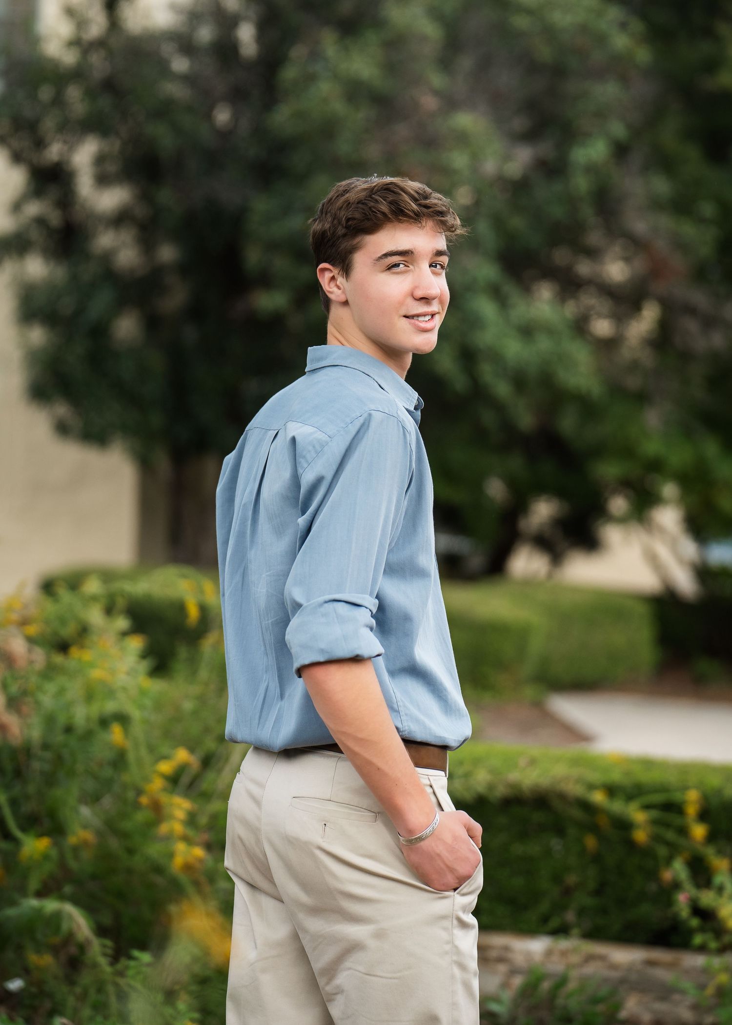 high school senior boy in blue shirt looking over his shoulder in Landa Gardens in San Antonio Texas