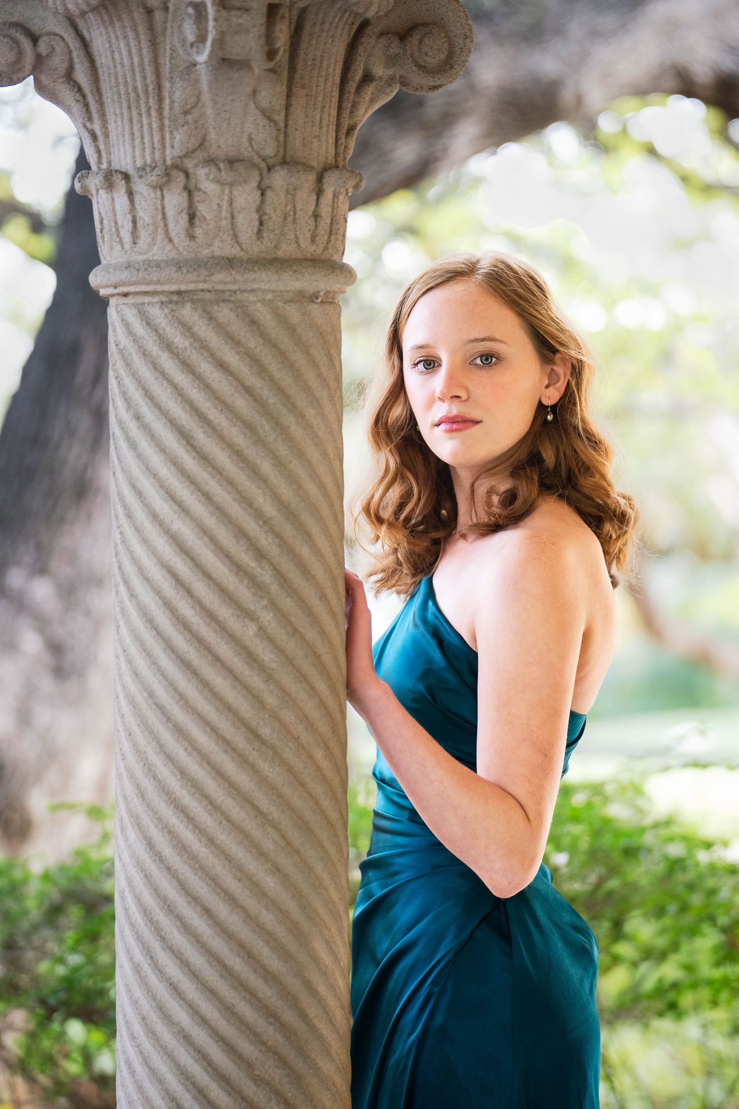 high school senior girl in formal green dress near pillar on Landa Library porch
