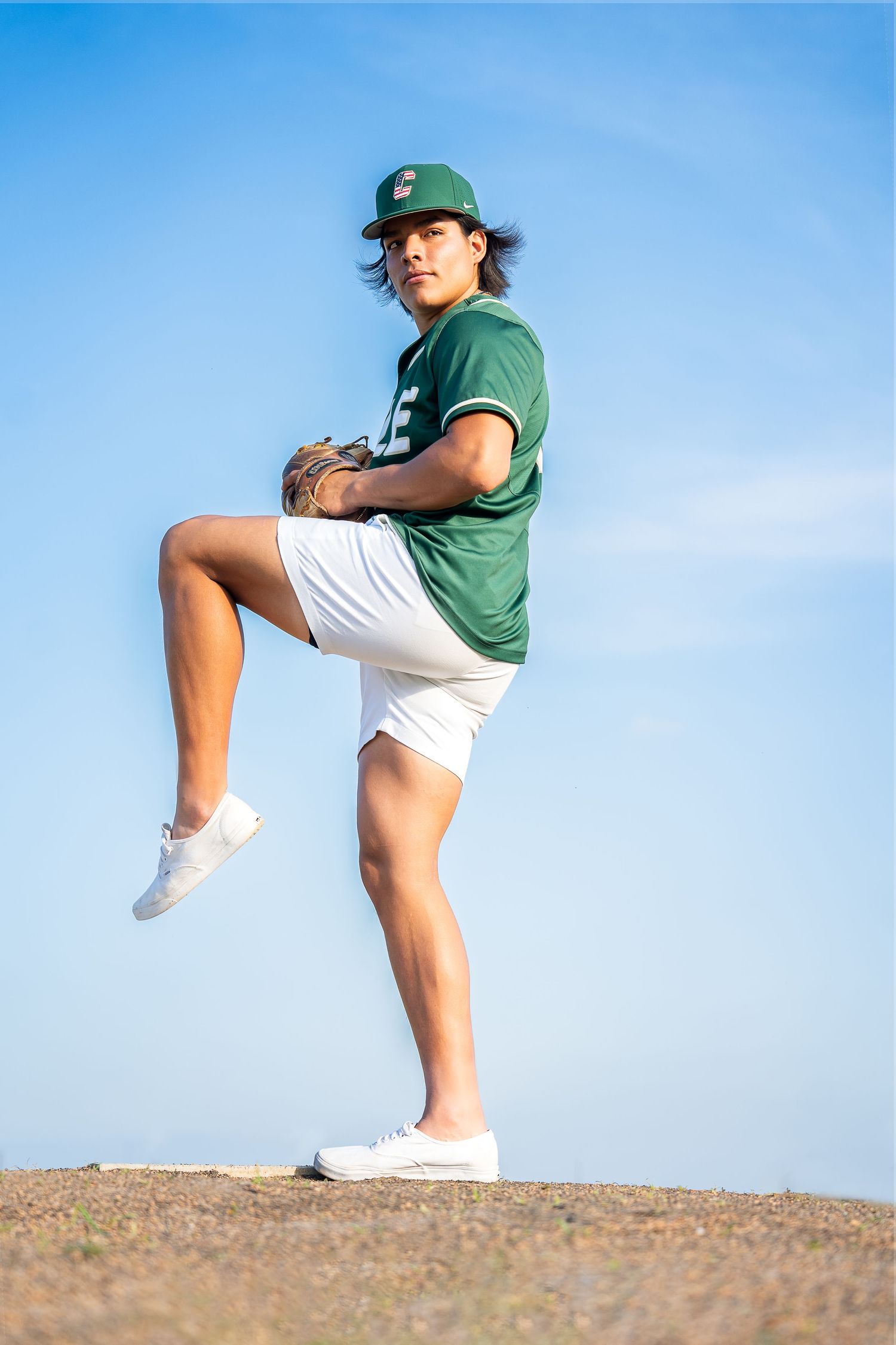 high school senior boy wearing green baseball jersey standing on pitchers mound in San Antonio Texas