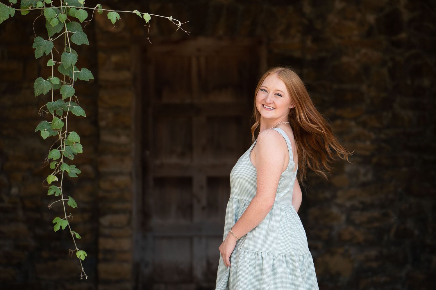 high school senior girl looking over her shoulder swinging her hair with green ivy hanging down in San Antonio Texas