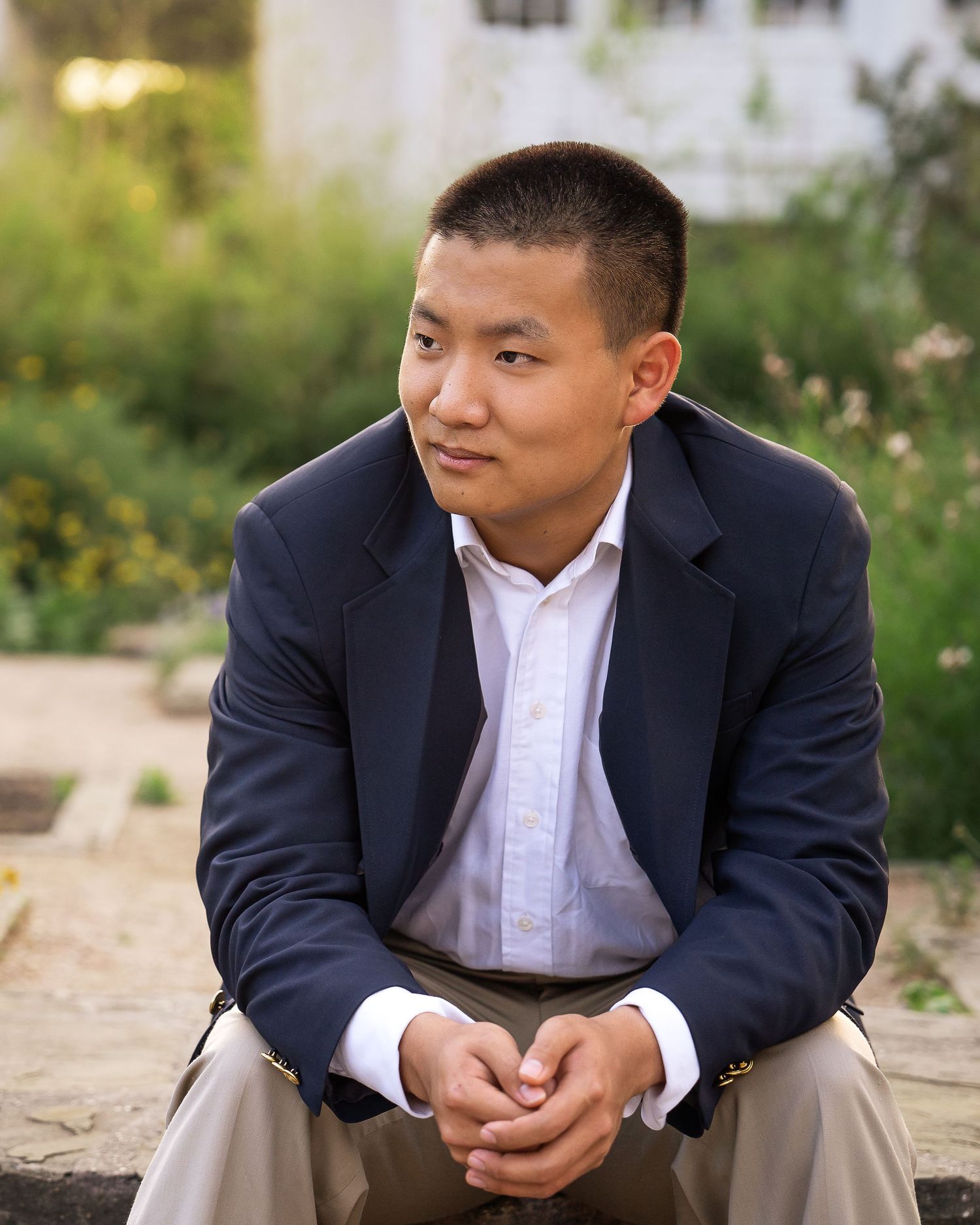 high school senior boy wearing navy blazer sitting on steps of Landa Gardens