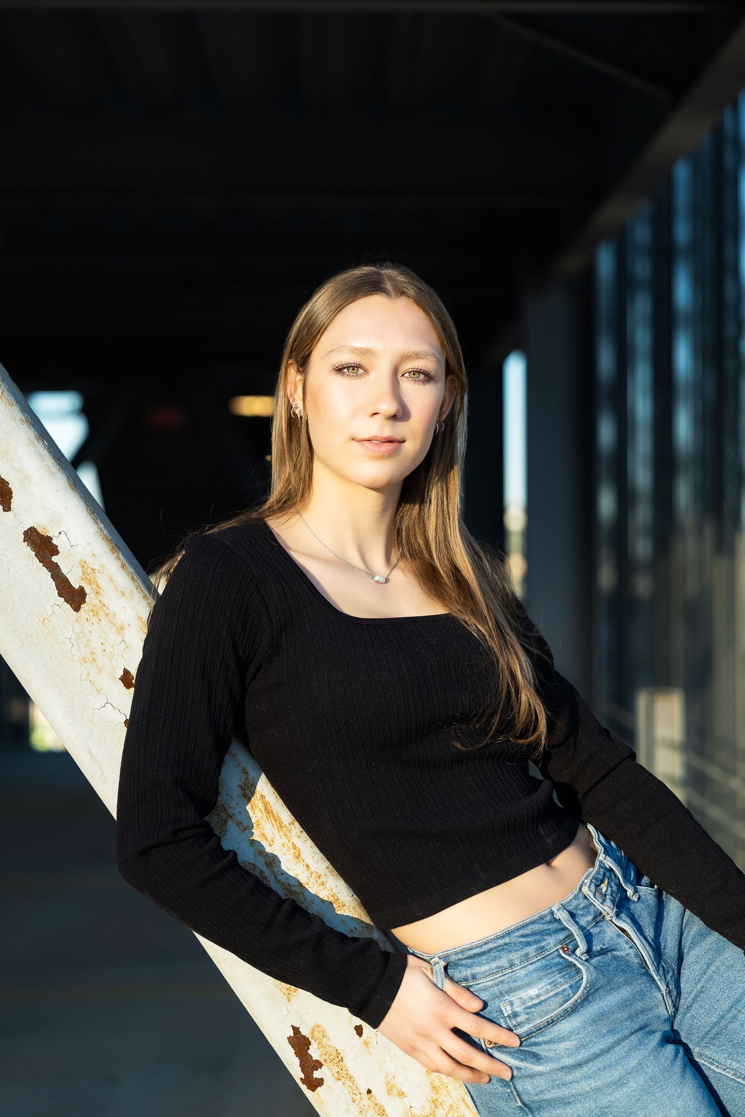 high school senior girl in black sweater resting on beam in parking garage