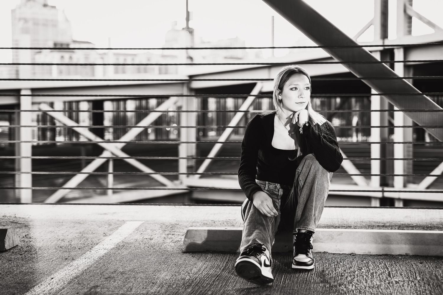 black and white portrait of high school senior girl sitting on parking block