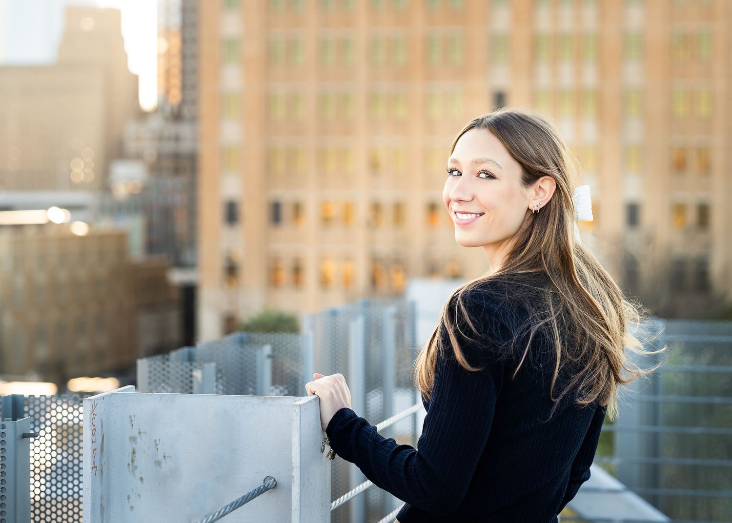 high school senior girl looking over her shoulder with city view behind her
