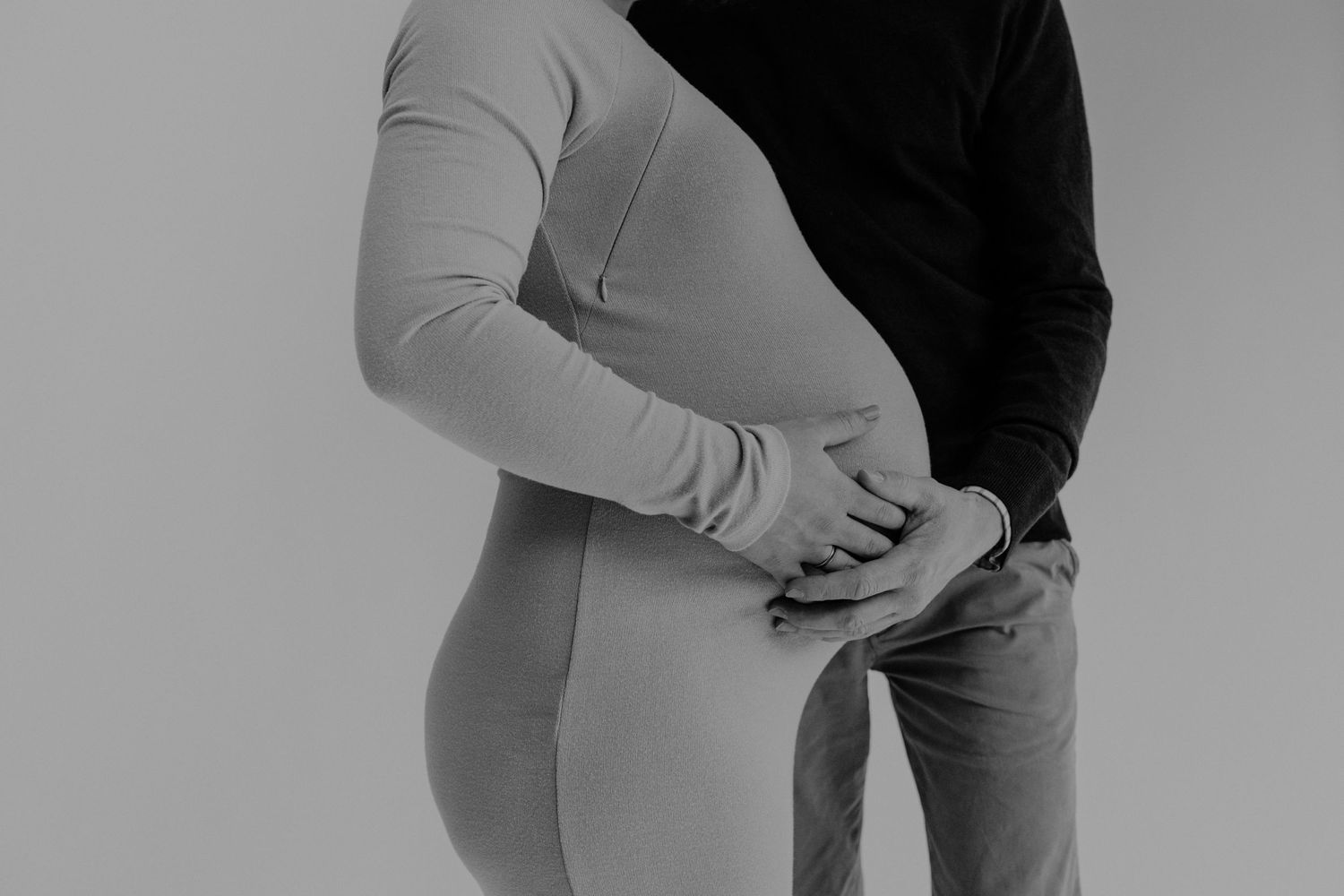 Ein Mann hält den Babybauch seiner schwangeren Frau. Profilaufnahme.