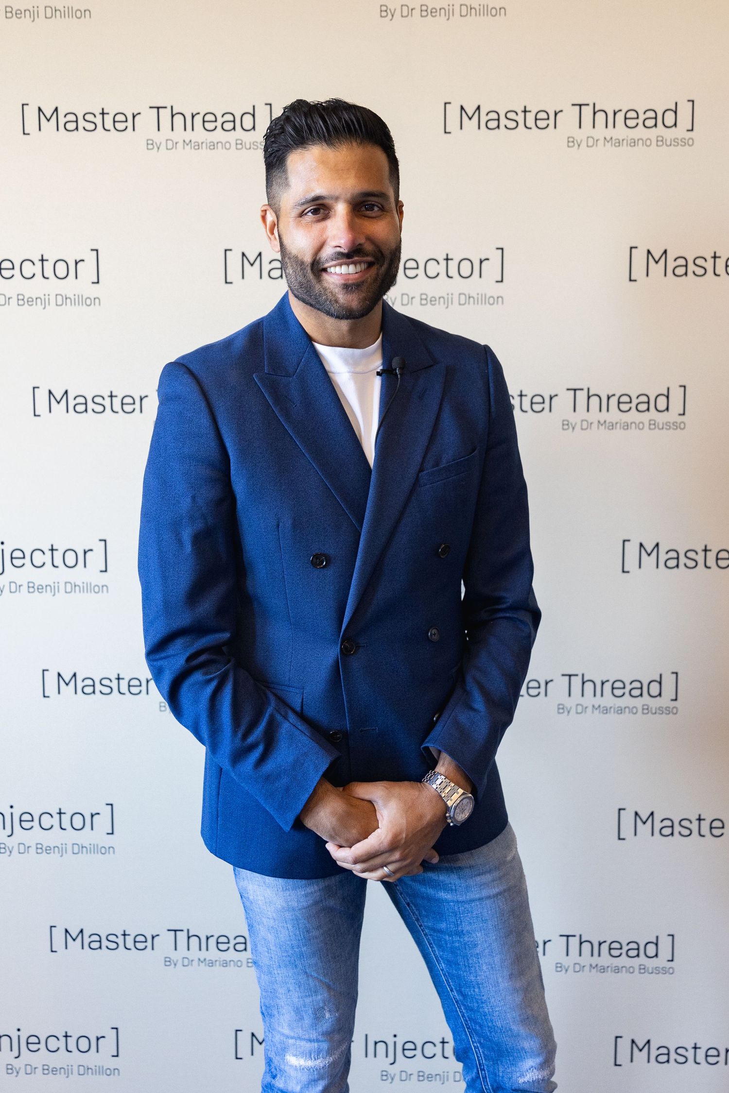 A person in a navy blue blazer and jeans poses against a backdrop with Master Thread branding.
