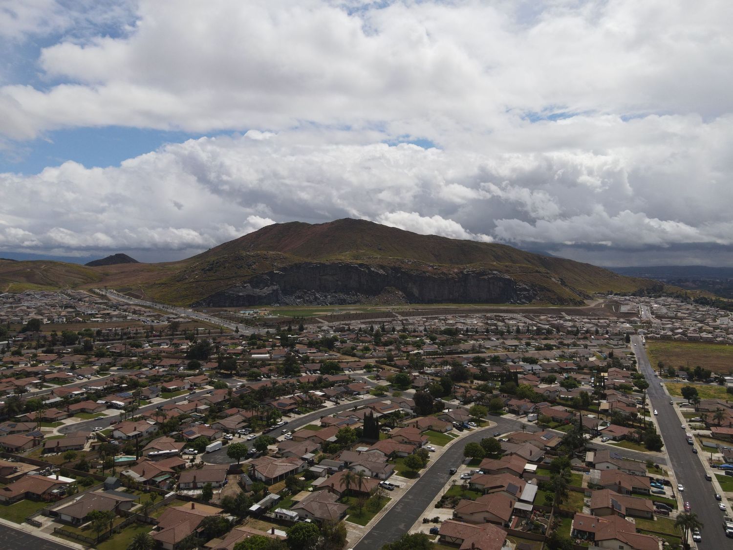 Aerial view of a Southern California suburban neighborhood with a large hill and cloudy sky.