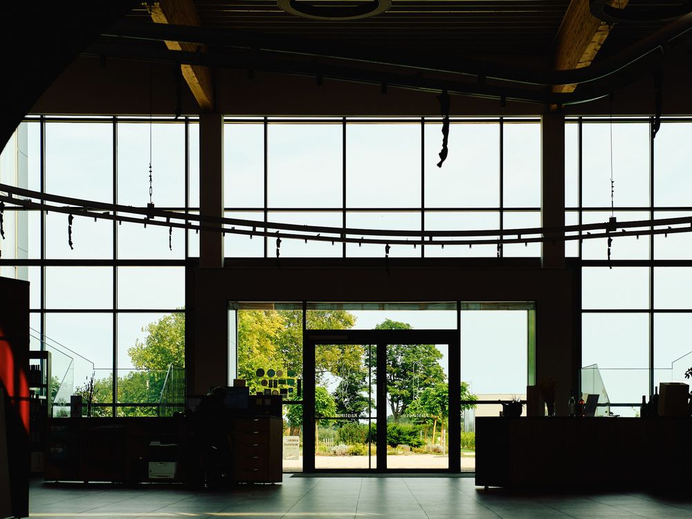 Large open industrial space with floor-to-ceiling windows and glass entrance doors.