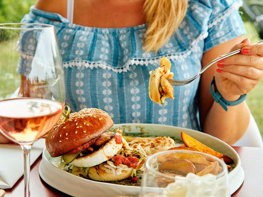 Casual dining scene with gourmet burger and rose wine on outdoor patio.