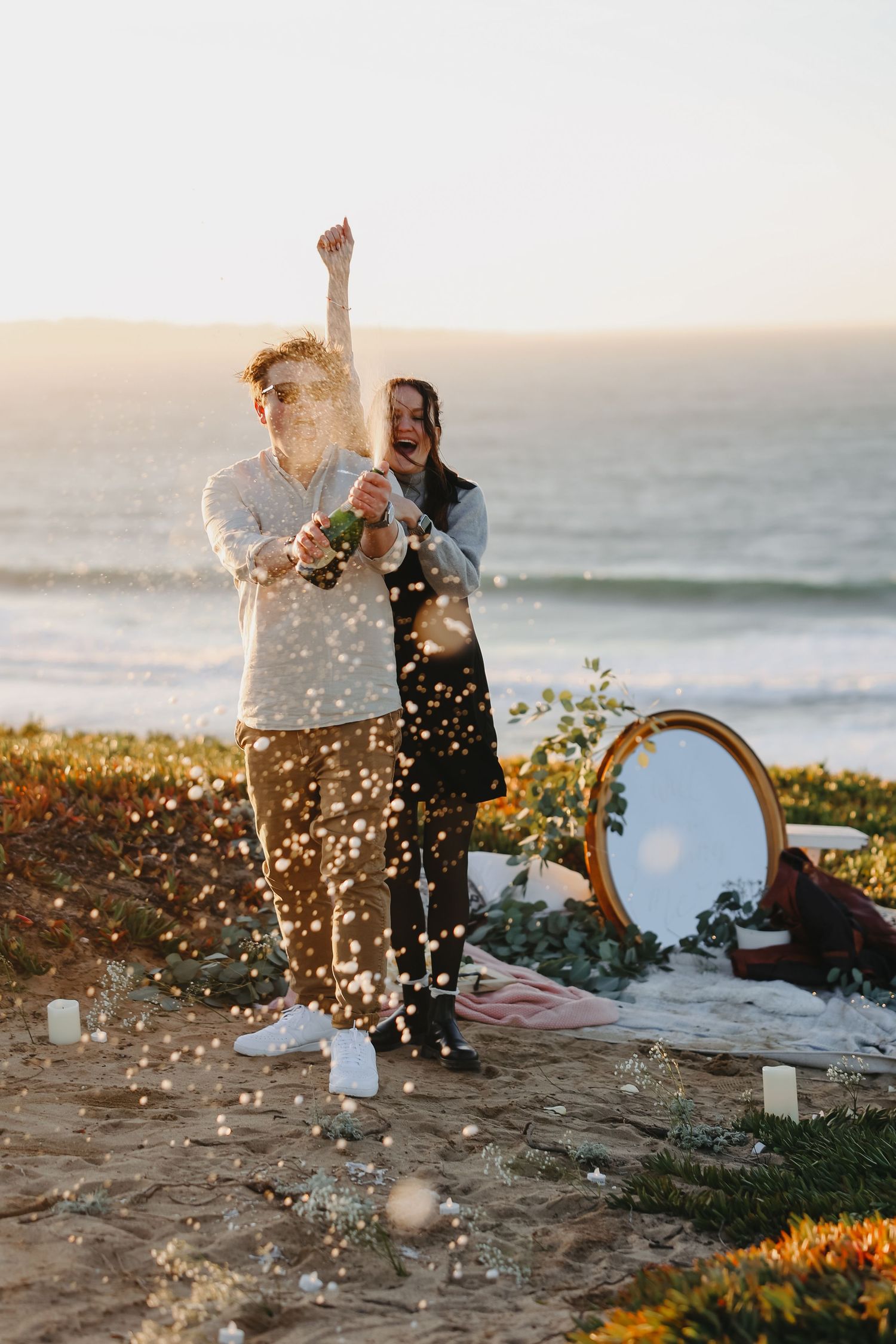 A celebratory moment with champagne and confetti by the ocean at sunset.