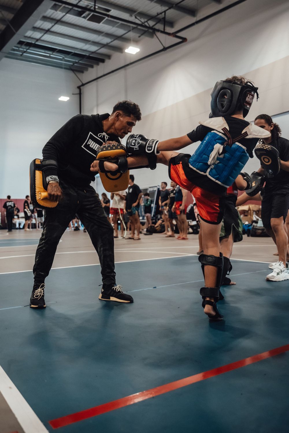 Low angle view of fighters practicing kicks and defensive moves on training mats.