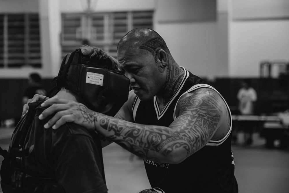 Two boxers practicing defensive techniques in a martial arts gym during training.