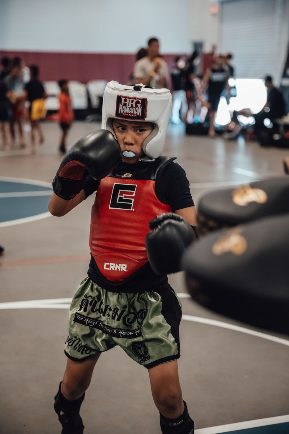 Martial arts student wearing red chest protector and camo shorts during combat training.