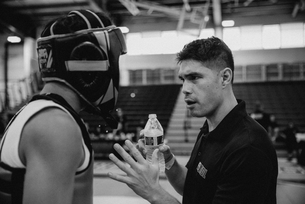 Martial arts students sparring with protective gear in a training facility.