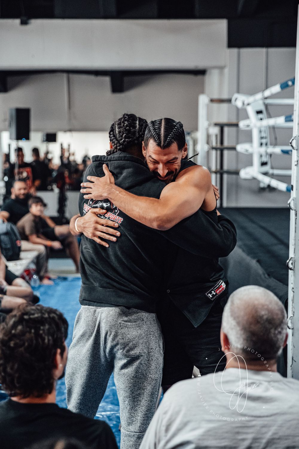Training partners embracing during a martial arts practice session in a gym.