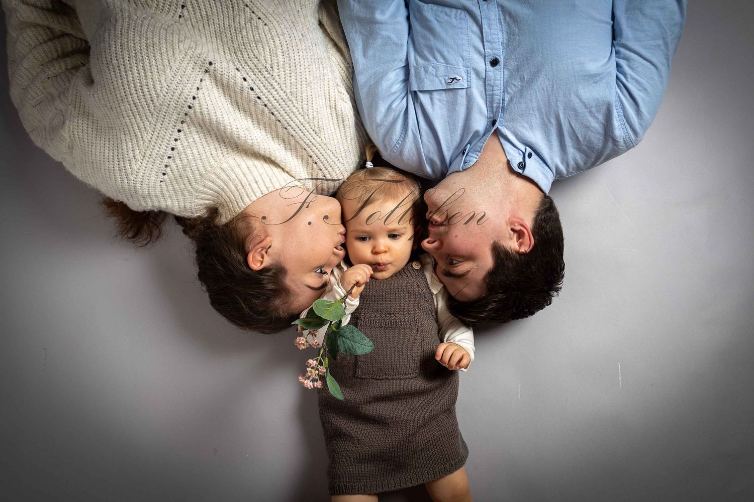 Loving parents lying down with their baby between them in a heartwarming family portrait photo.