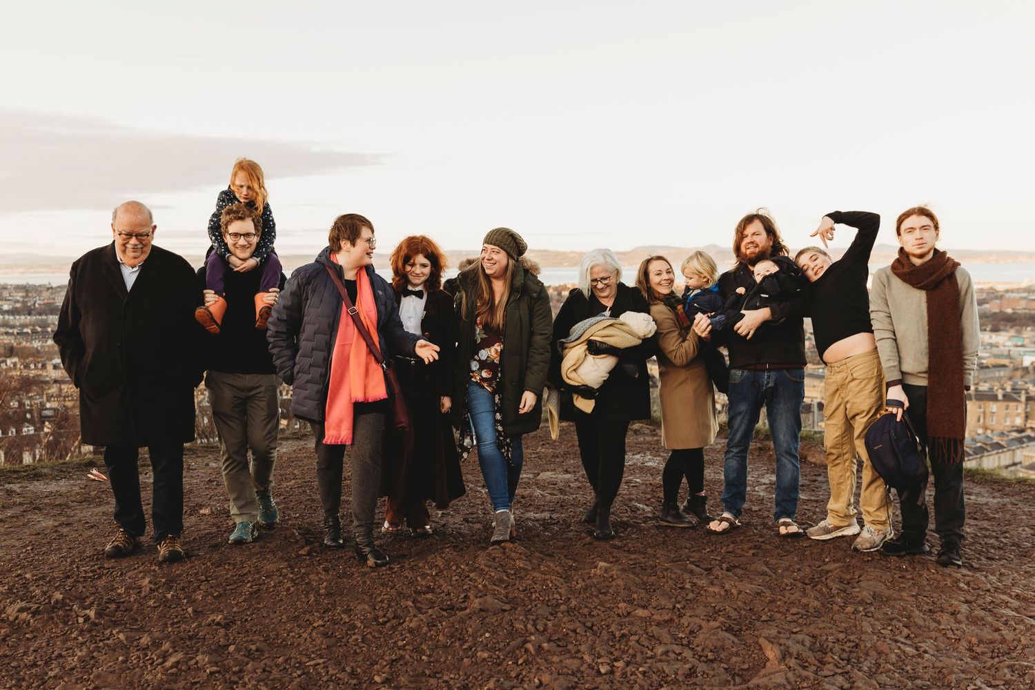 Group of people posing together on a hilltop against an overcast sky.