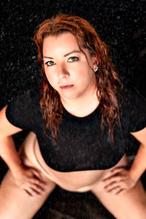 Studio portrait with rain effect against black background.