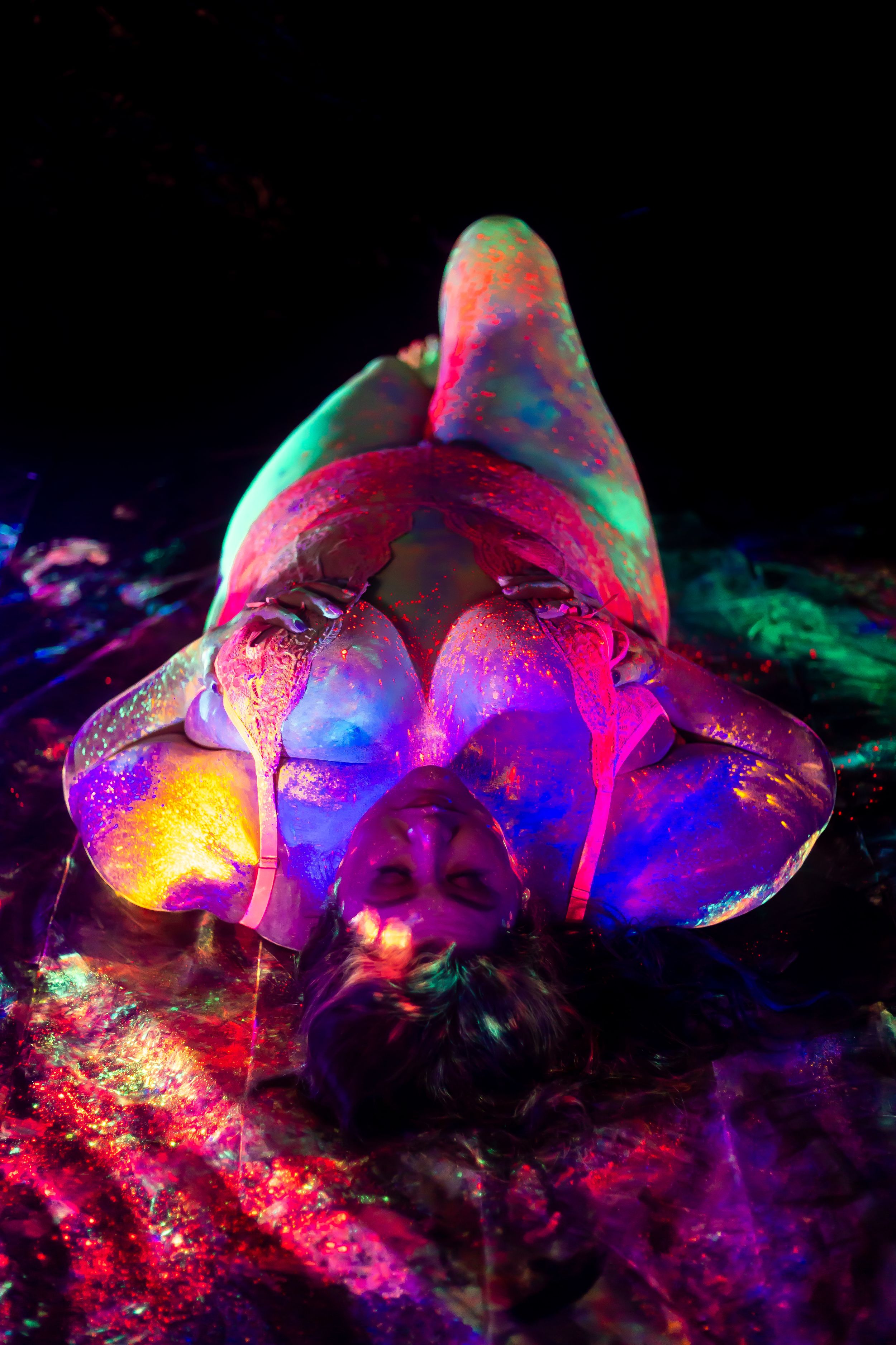 Glowing mushrooms illuminated with colorful neon lights creating a psychedelic effect against black background.