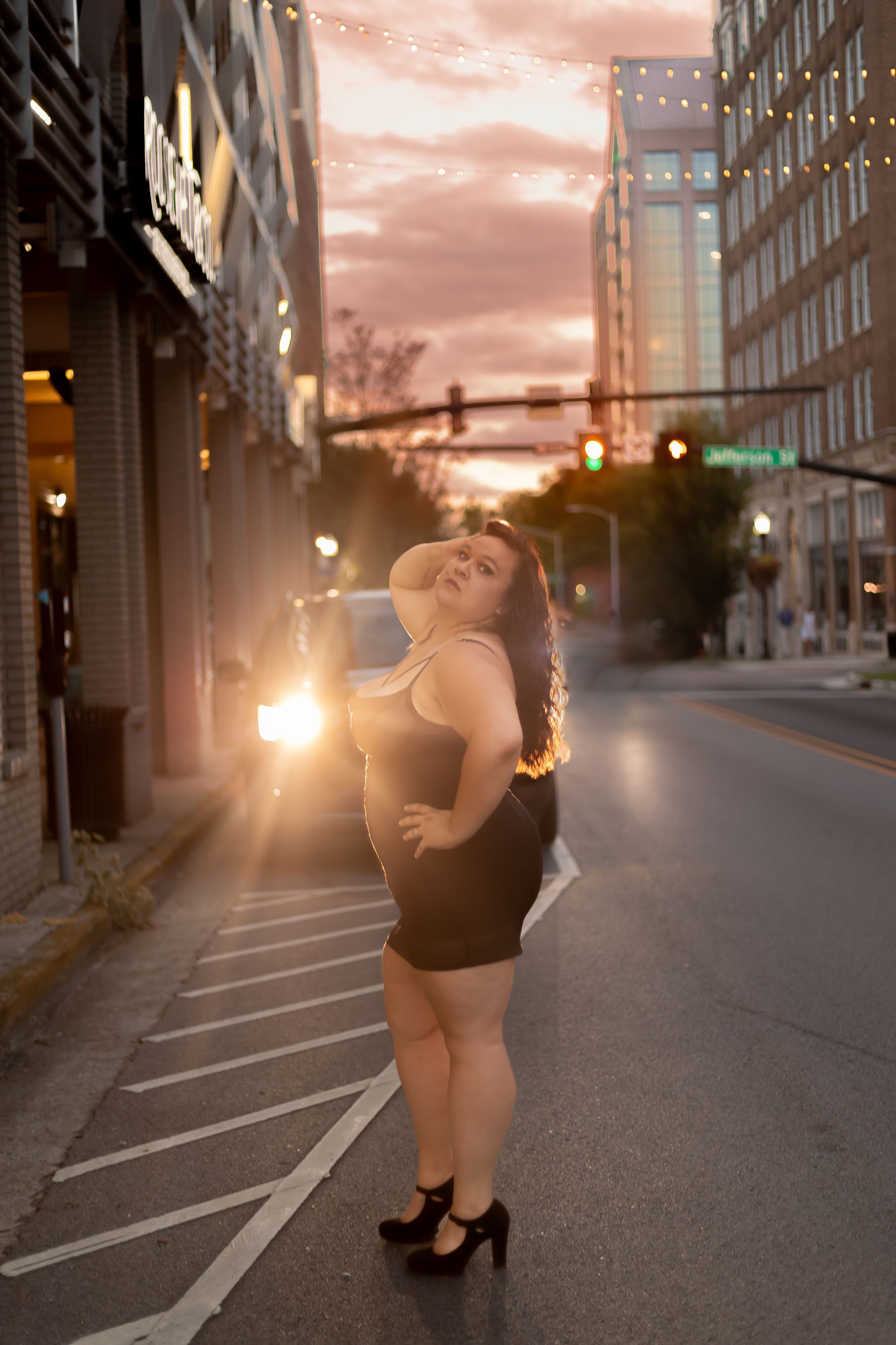 Urban sunset portrait on city street with string lights and warm evening glow.