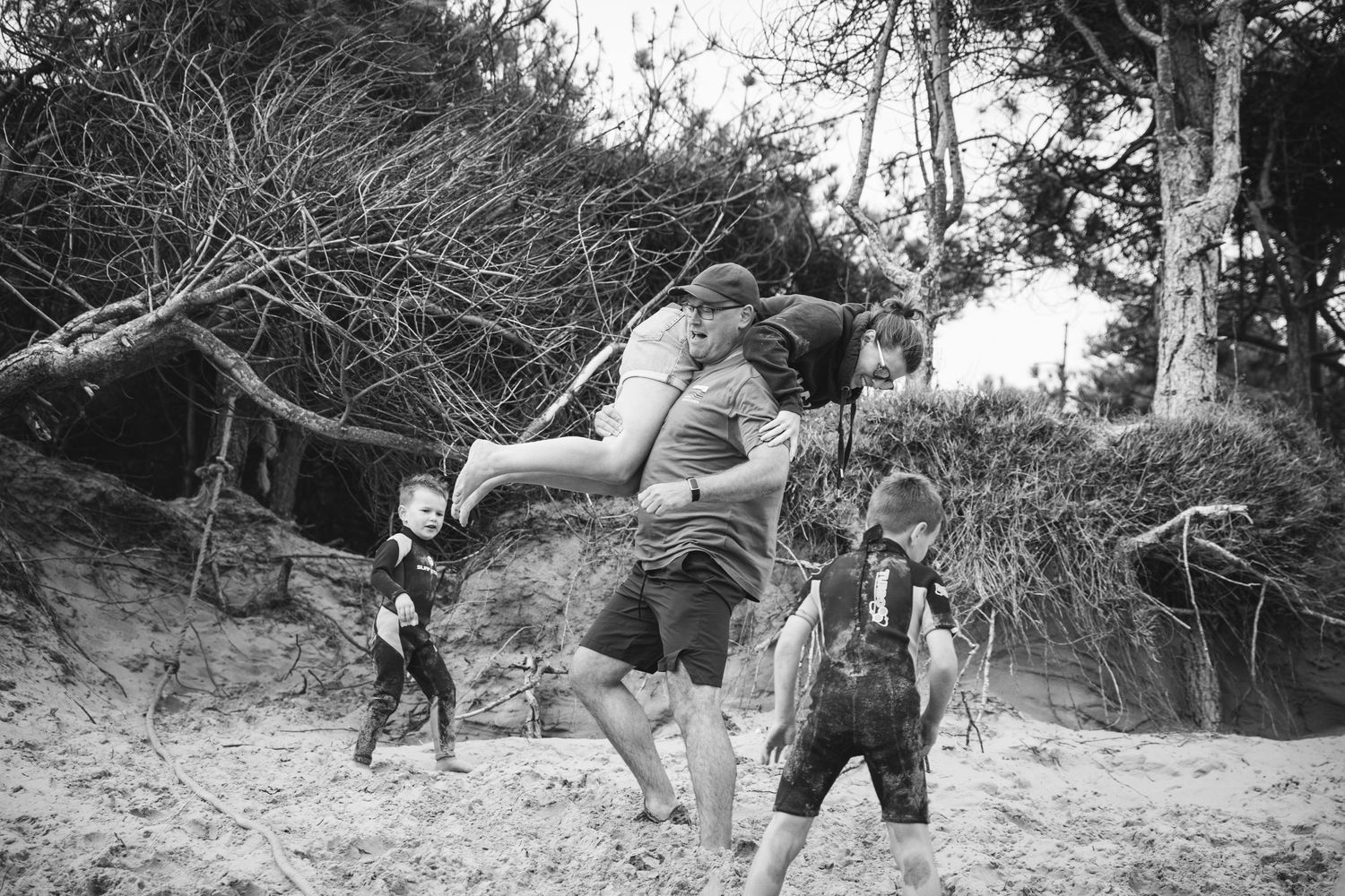 Playful group enjoying outdoor activities on sandy terrain in black and white photo.